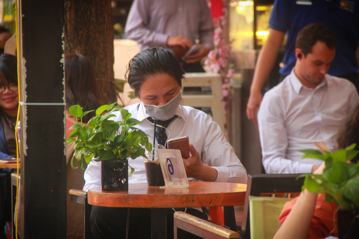 Trước nỗi lo lây lan virus corona, nhiều người vào uống cafe cũng vẫn phải đeo khẩu trang.