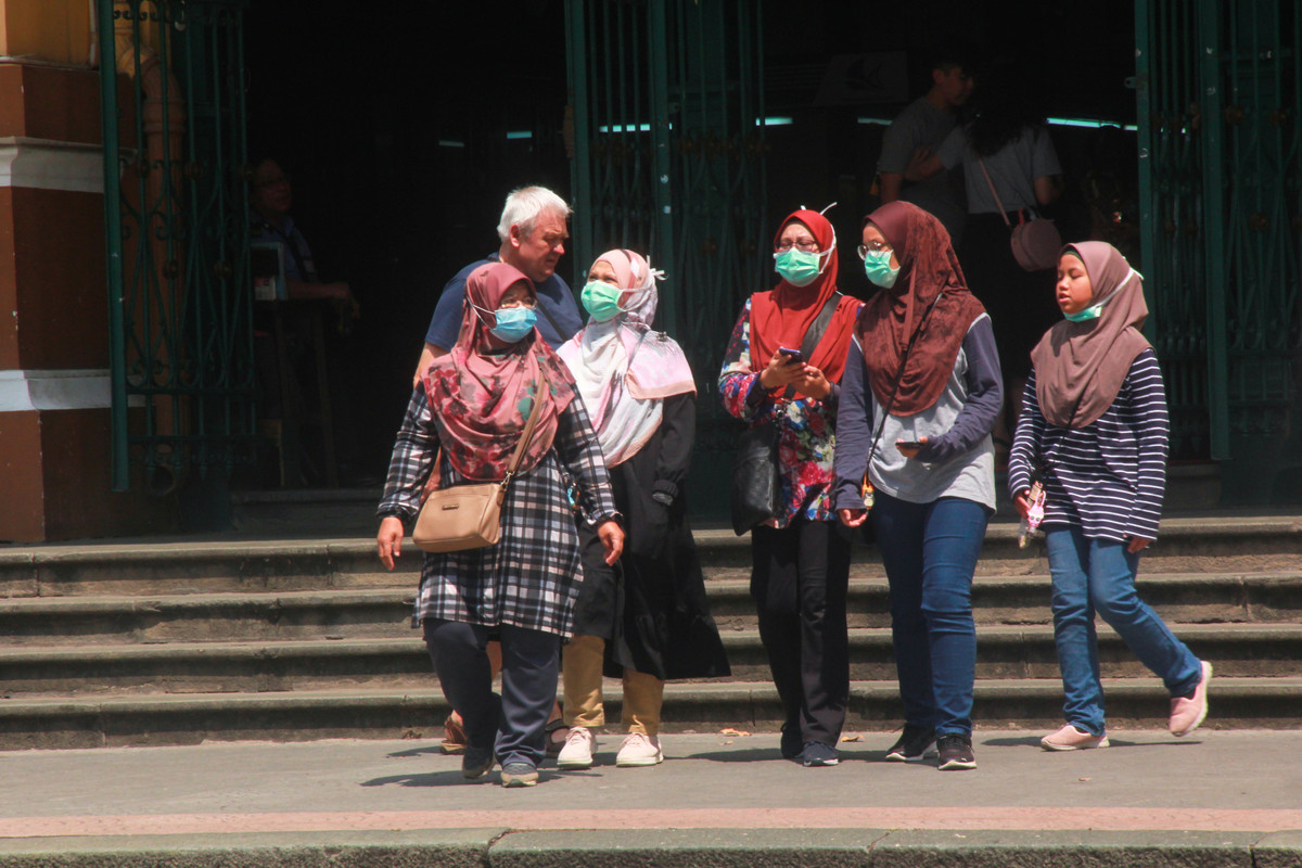 Du khách nước ngoài bịt kín khẩu trang khi tới thăm quan Bưu điện thành phố.