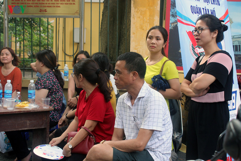 Phụ huynh Hà Nội đội nắng đợi con làm bài thi ngoài cổng trường.