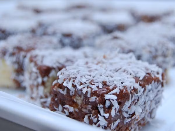 Bánh Lamingtons, niềm tự hào của người Úc. Thành phần làm bánh bao gồm: trứng, bột mì, bột ngô, bơ, đường cát, bột cacao, và dừa sấy.