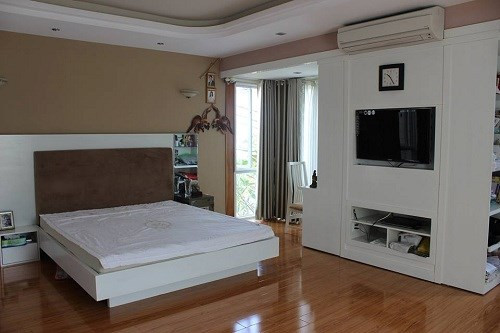 Phòng ngủ chính của vợ chồng anh Mỹ lấy màu trắng làm chủ đạo, kệ tủ áp tường 3 chiều thông minh sử dụng cho nhu cầu giải trí và làm việc.