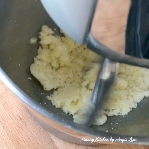 Cho bơ và đường vào bát trộn của máy trộn bột rồi trộn với tốc độ vừa đến khi thành dạng nhão. Trong khi trộn chú ý vét đều bơ đính trên thành bát xuống. 