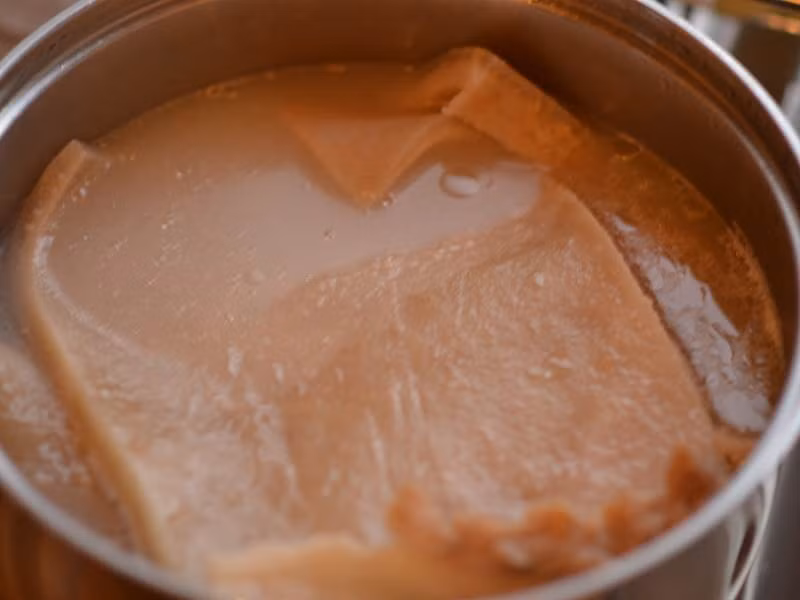 Cho da lợn vào nồi to và đổ nước vào, dùng một cái đĩa đặt lên trên để da lợn chìm xuống. Bật bếp luộc da lợn đến khi da mềm và cuộn tròn được. Thời gian luộc từ 1,5 – 2 giờ và nước luộc phải có màu trắng mới ngon. Trong quá trình luộc cho thêm nước vào nếu cần. (Ảnh: bdws)