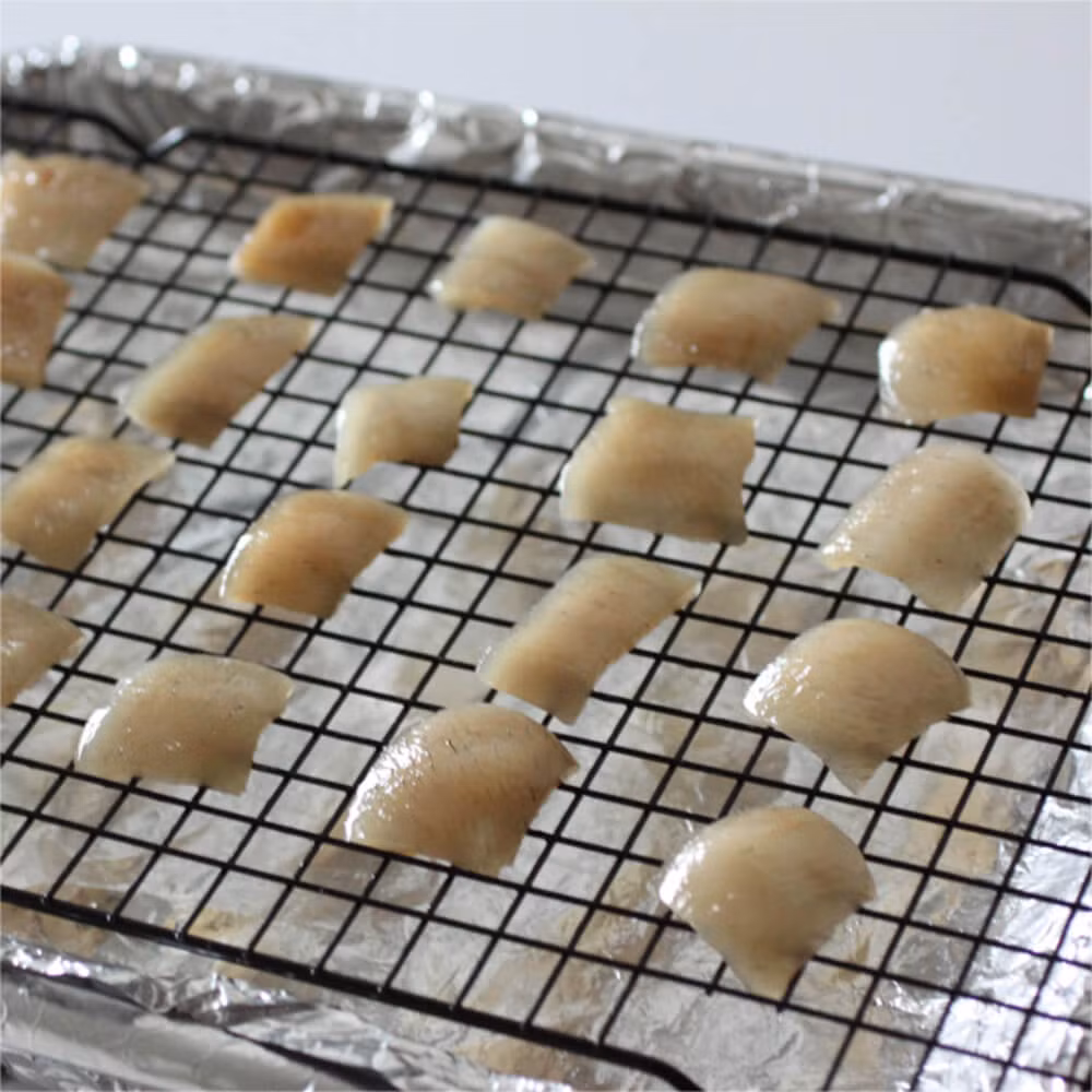 Dùng dao lạng bỏ hết mỡ ở mặt trong của da heo, lưu ý cẩn thận không làm da heo bị rách. Cho da heo vào khay nướng, đặt nhiệt độ lò nướng ở mức thấp nhất (khoảng 93 độ C) và để qua đêm cho khô. Lúc này da heo sẽ chuyển màu nâu và dễ gãy. (Ảnh: baconheir)