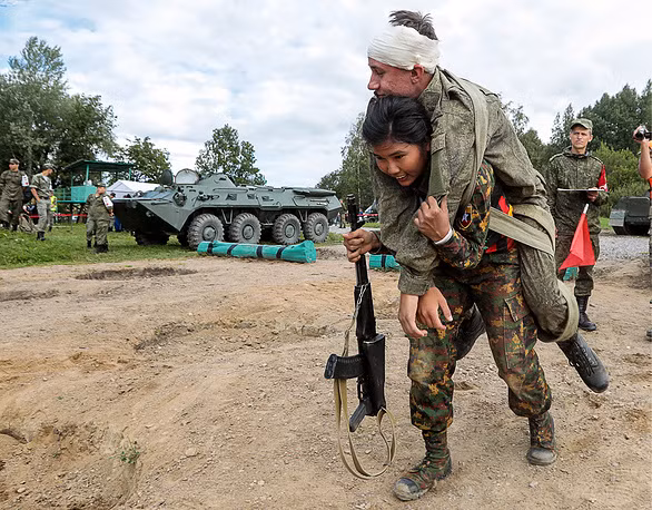 Ở phần thi cứu thương, nhiều nữ quân y phải cõng "thương binh" nặng tới hàng trăm kilograms. Trong ảnh là một nữ quân y của đội Myanmar đang cõng một người lính Nga trên vai. Nguồn ảnh: TASS.