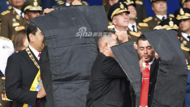 Sau đó, Tổng thống được ngay lập tức dẫn tới khu vực an toàn, lên xe và rút khỏi nơi xảy ra vụ việc. Do mục tiêu là một máy bay không người lái nên những cận vệ của ông Maduro hoàn toàn không rút súng ra sử dụng. Nguồn ảnh: Sina.