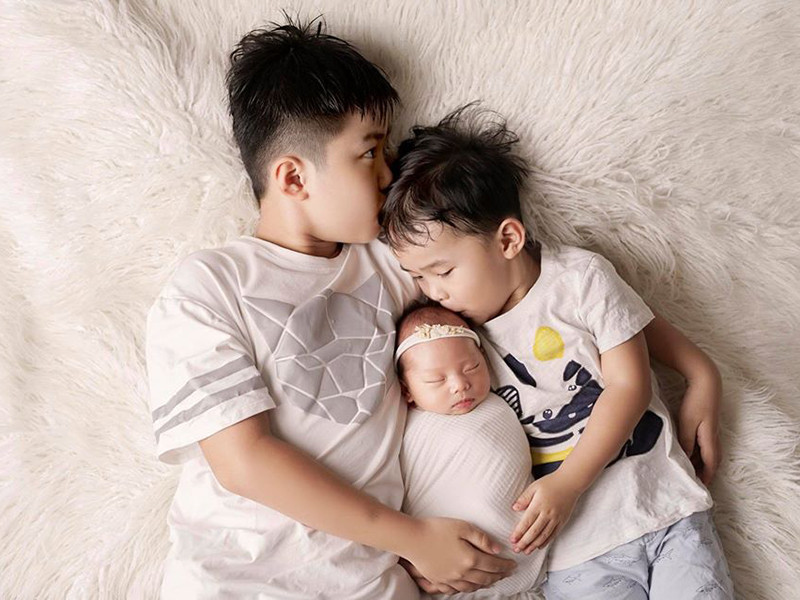 Bé Minh Hà được hai anh trai cưng nựng.