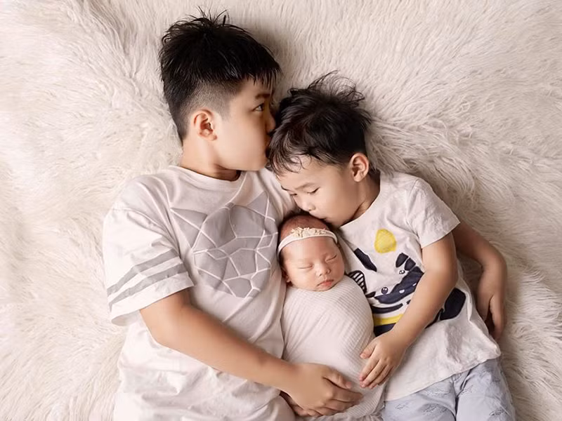 Bé Minh Hà được hai anh trai cưng nựng.
