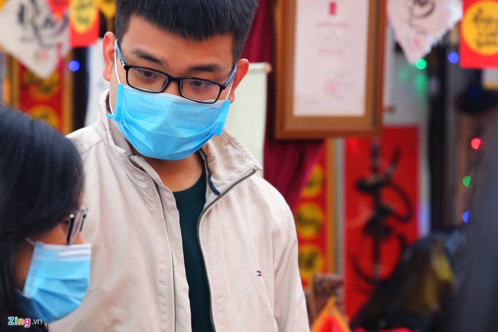 Hai bạn trẻ cố gắng hội thoại với nhau qua chiếc khẩu trang y tế khi đứng chờ xin chữ thư pháp.
