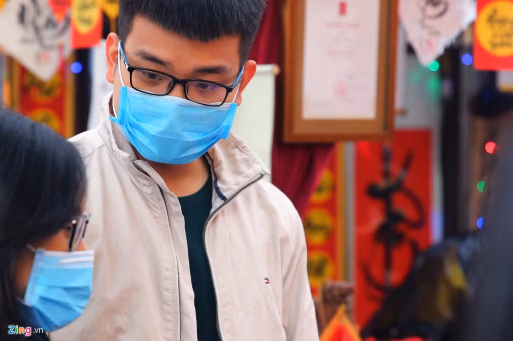 Hai bạn trẻ cố gắng hội thoại với nhau qua chiếc khẩu trang y tế khi đứng chờ xin chữ thư pháp.