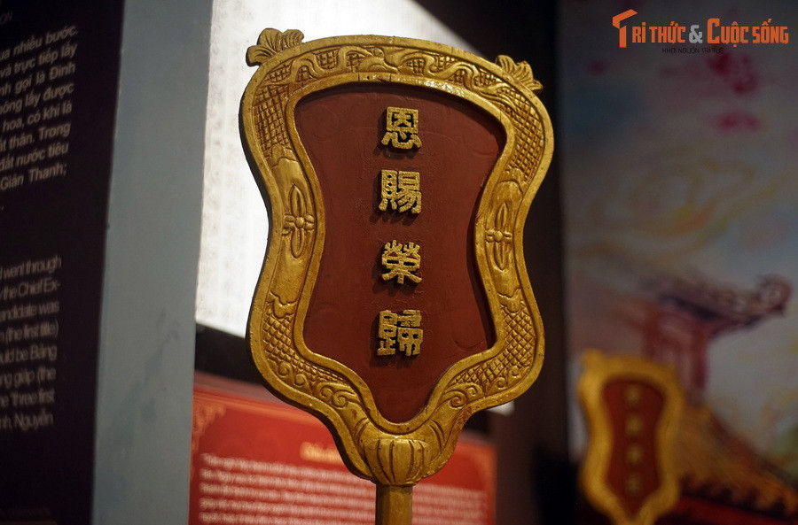 Đi sau người cầm cờ là người cầm tấm biển sơn son, mặt trước có bốn chữ vàng "Ân tứ vinh quy", mặt sau khắc tên tuổi thứ hạng đỗ đạt.