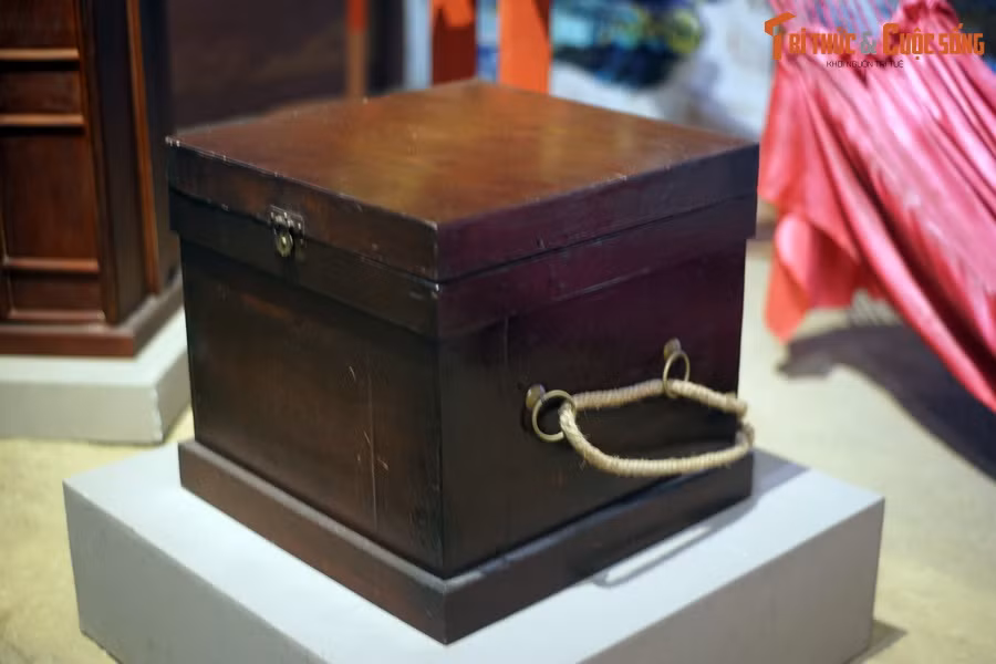 Một người cầm hộp đựng sách vở của Tiến sĩ đi sau võng cáng. Những chiếc hộp này thường được đóng bằng gỗ, có khóa và cánh cửa giống như một chiếc tủ nhỏ, có thể có quai xách hoặc không.