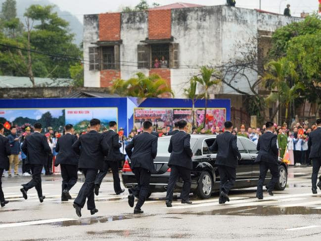 Theo đó trong mọi tình huống kể từ lúc Chủ tịch Kim Jong-un đặt chân xuống Ga Đồng Đăng vào sáng 26/2, đội cận vệ Triều Tiên gồm 12 người chịu trách nhiệm bảo vệ Chủ tịch Kim Jong-un luôn theo sát ông Kim không rời một bước. Nguồn ảnh: DCS.