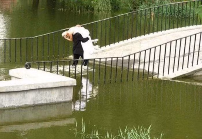 Người đàn ông bế cô gái qua cây cầu bị ngập nước. Ảnh: ER.