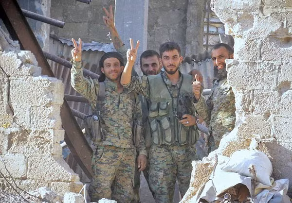 Các binh sĩ Syria giơ tay biểu tượng chiến thắng trên chiến trường Đông Damascus. Ảnh: FNA.