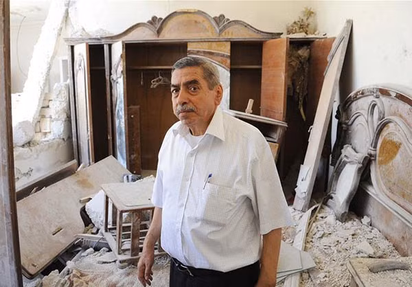 Người đàn ông xem xét bên trong ngôi nhà bị hư hại do các cuộc giao tranh ở Aleppo trước đây. Ảnh: FNA.