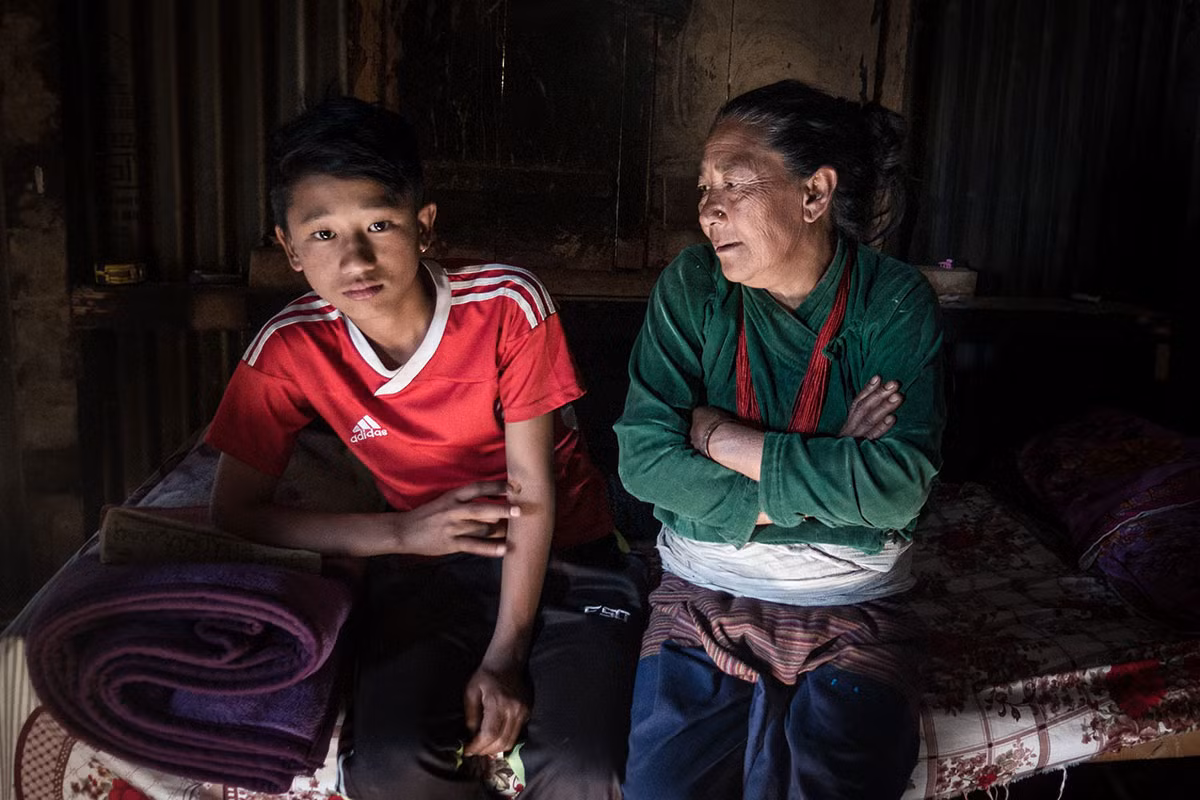 Ramaya Tamang, 65 tuổi, trò chuyện với cháu trai Bikek, 16 tuổi, trong nhà ở huyện Sindhulpachok. Được biết, bà Tamang đã chăm sóc hai anh em Bibek suốt gần 10 năm nay do mẹ của Bibek tới Iraq làm việc, còn cha của Bibek đã qua đời khi làm việc tại Ả-rập Xê-út. Ảnh: AJ.