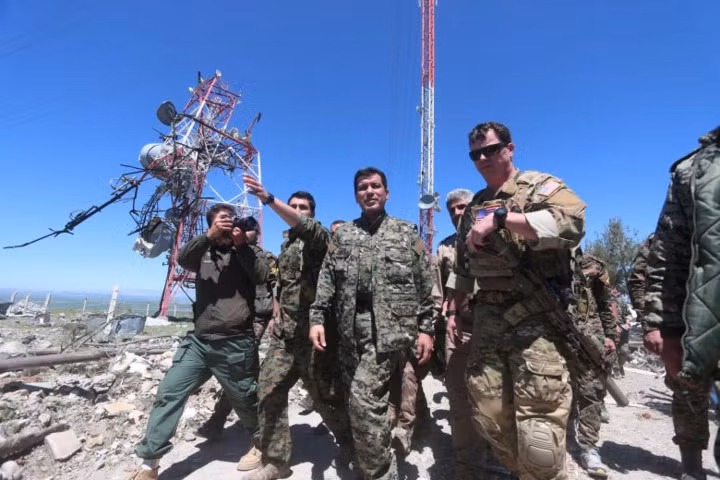 Chỉ huy Mỹ (phải) đi bên cạnh một chỉ huy YPG khi họ đi kiểm tra tổng hành dinh YPG vừa trúng bom của máy bay Thổ Nhĩ Kỳ. Nguồn ảnh: Reuter.