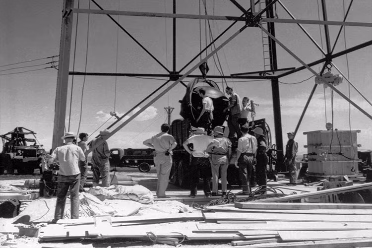 Rạng sáng ngày 16/7/1945, vụ thử Trinity được triển khai tại sa mạc Jornada del Muerto nằm cách Socorro, New Mexico khoảng 56 km về phía Đông Nam. Tham gia vào vụ thử này là hơn 400 người đến từ các cở sở nghiên cứu thuộc dự án Manhattan. Trong ảnh là "The Gadget" được kéo lên một ngọn tháp cao 30m mô phỏng cho quá trình quả bom được kích hoạt trên không. Nguồn ảnh: cloudfront.net.