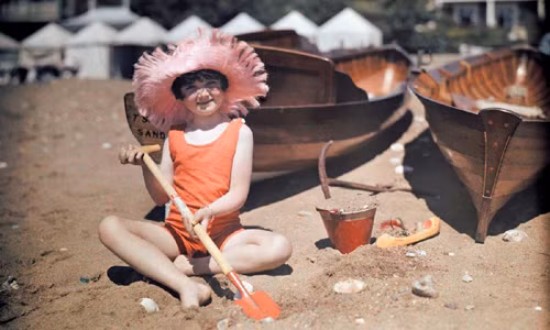 Bé gái thích thú ngồi nghịch cát ở Sandown, Isle of Wight.