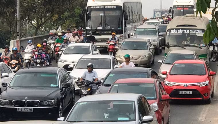 Người đi xe máy kẹt cứng giữa dòng ôtô, xe khách trong thời tiết nắng nóng mùa khô miền Nam để đến bến xe tìm đường về quê nghỉ Tết.