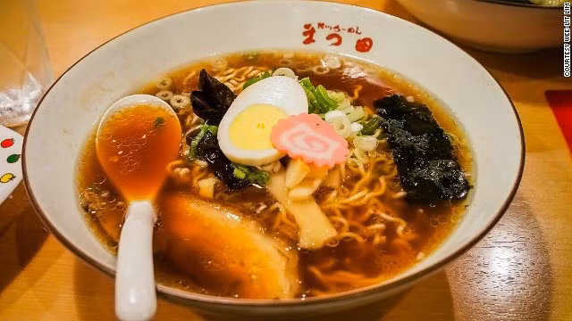 Trong bát có những sợi mì nhỏ được chan nước dùng gà hoặc lợn béo ngậy, thêm hành tươi, thịt lợn và trứng trần.