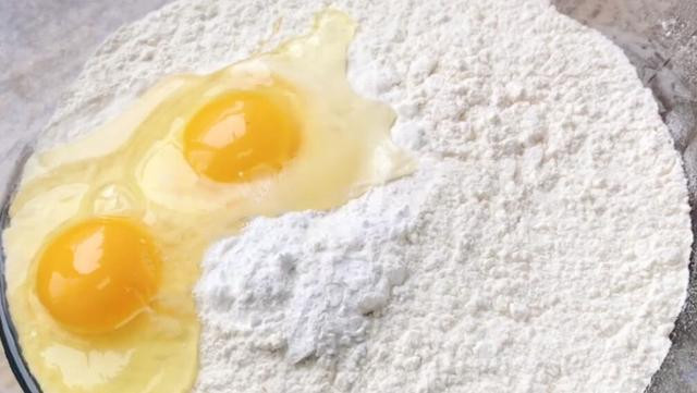 Thành phần: 500g bột mì, 2 quả trứng, 300ml sữa, 5g bột nở và dầu ăn。 Đầu tiên, ta cho bột vào bát, sau đó đập trứng vào, cho bột nở, dùng đũa khuấy đều.