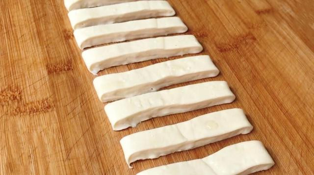 Khi bột đã ủ đủ giờ, ta chia bột. Phết lớp dầu ăn lên thớt. Lúc này ta không cần nhào bột nữa, bột đã cứng hơn, ta dễ dàng kéo và lăn bột thành dải dài và dày. Dùng dao cắt thành dải rộng khoảng 2 ngón tay.