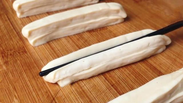 Bôi nhẹ nước trên các sợi bột, sau đó đặt 2 sợi lại, dùng đũa ấn nhẹ để chúng dính vào nhau. Dùng tay bóp nhẹ 2 đầu để 2 sợi bột không tách rời.