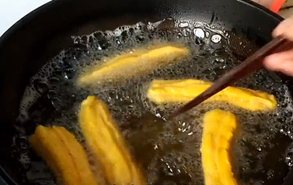 Sau khi miếng quẩy đã nổi lên, liên tục đảo để quẩy nóng đều.