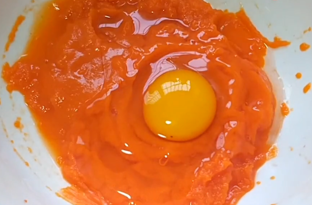 Nghiền nát cà rốt rồi cho 1 quả trứng vào, cùng 3g muối, 3g bột nở đánh đều.