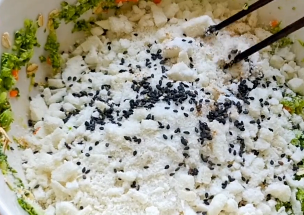 Sau khi trộn đều, thêm một nửa chiếc bánh bao ngọt đã bóp nhỏ, thêm một lượng nhỏ mè đen, hạt tiêu, muối và trộn đều.