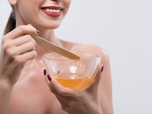 Sử dụng sáp tẩy lông: Dùng sáp tự làm tại nhà cũng là một phương pháp tẩy lông mặt hiệu quả vì dễ làm, không tốn thời gian và không cần sử dụng miếng dán. Bạn chỉ cần trộn một lượng tương đương các nguyên liệu gồm nước cốt chanh, đường và nước rồi đun đến khi hỗn hợp có dạng đặc như sáp. Dùng que gỗ thoa sáp tẩy lông còn nóng trực tiếp lên da. Khi sáp nguội, giật mạnh lớp sáp để loại bỏ lông.