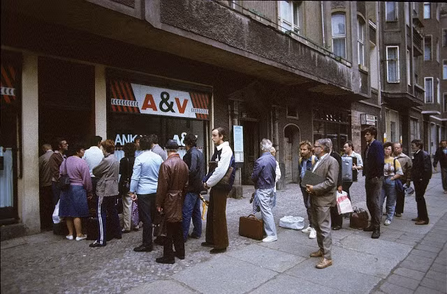 Người dân xếp hàng một cách trật tự phía trước một cửa hàng.