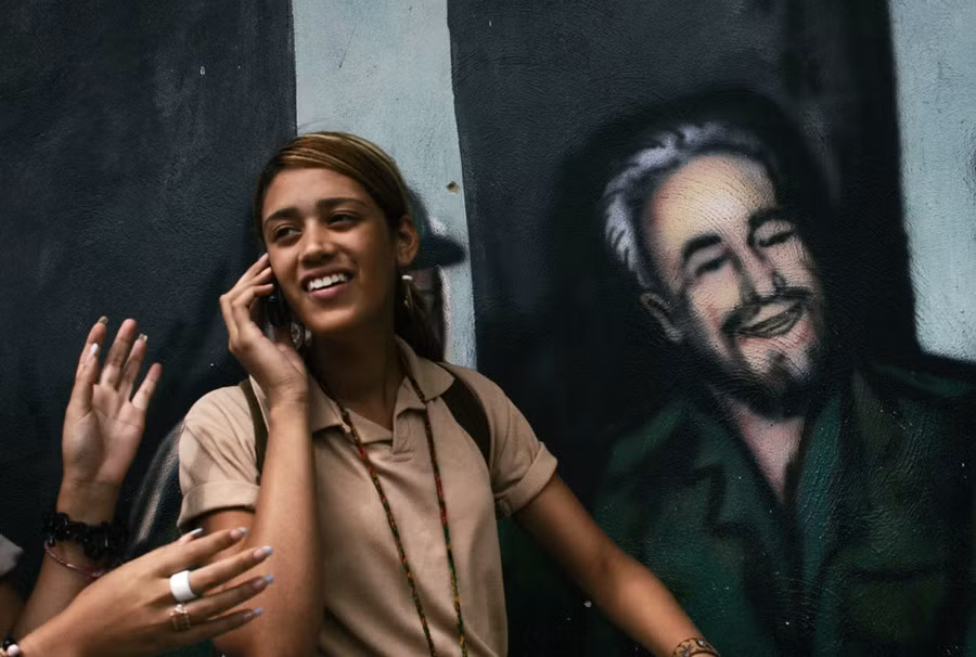 Nữ sinh Cuba đứng bên cạnh bức tranh graffiti vẽ nhà lãnh đạo Fidel Castro ở Caracas ngày 19/2/2008.