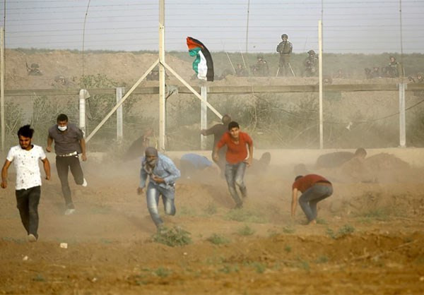Đám đông người biểu tình Palestine tháo chạy trong cuộc đụng độ với binh sĩ Israel. Ảnh: FNA.