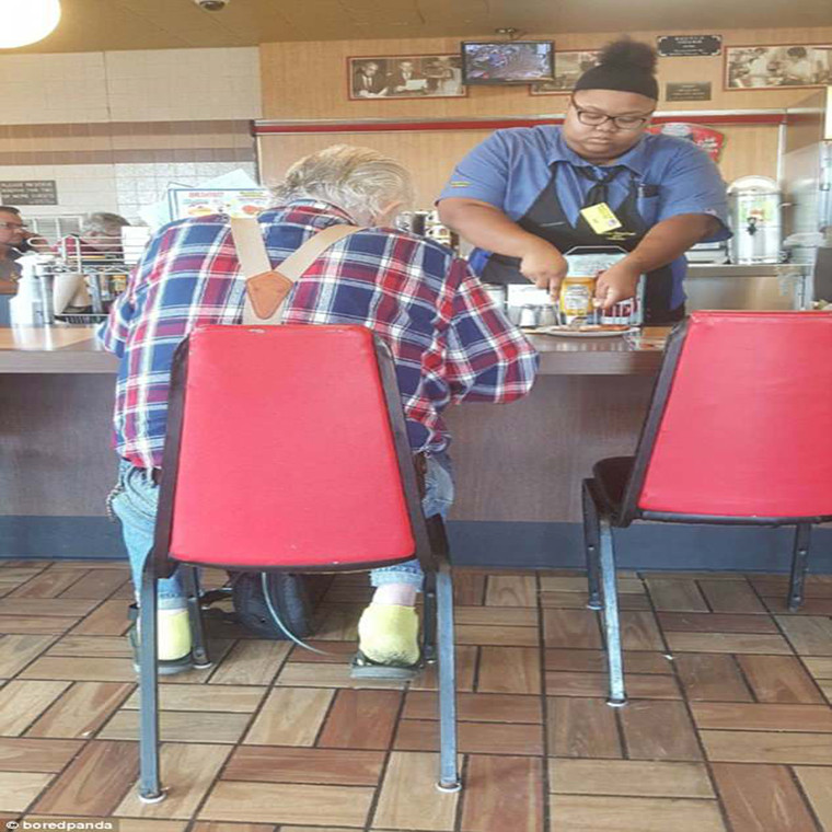 Nhân viên bán hàng thái đồ ăn giúp một thực khách lớn tuổi trong một nhà hàng.