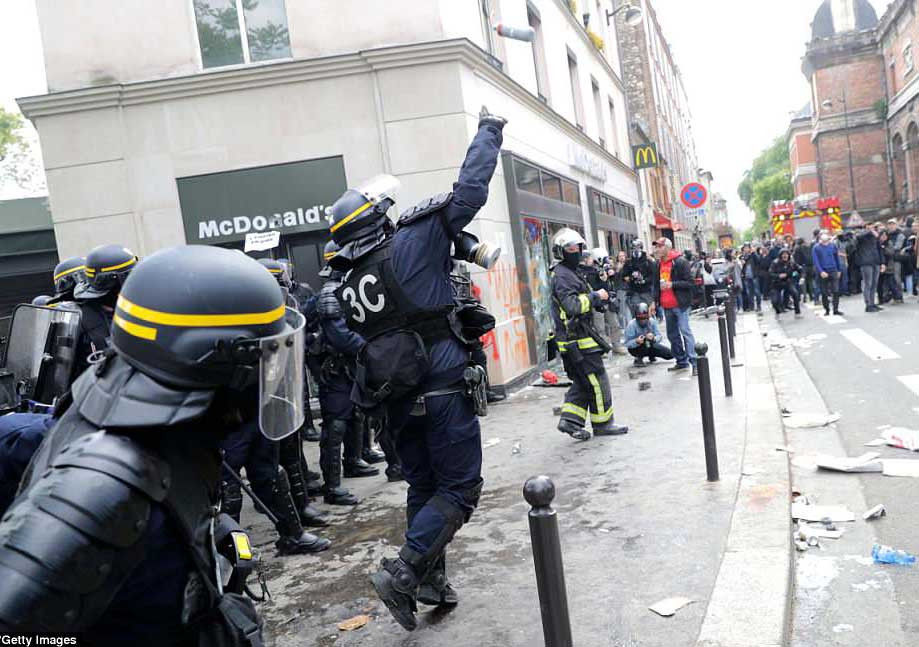 Cảnh sát chống bạo động Pháp ném lựu đạn hơi cay về phía những người biểu tình tập trung bên ngoài một cửa hàng McDonald hôm 1/5.