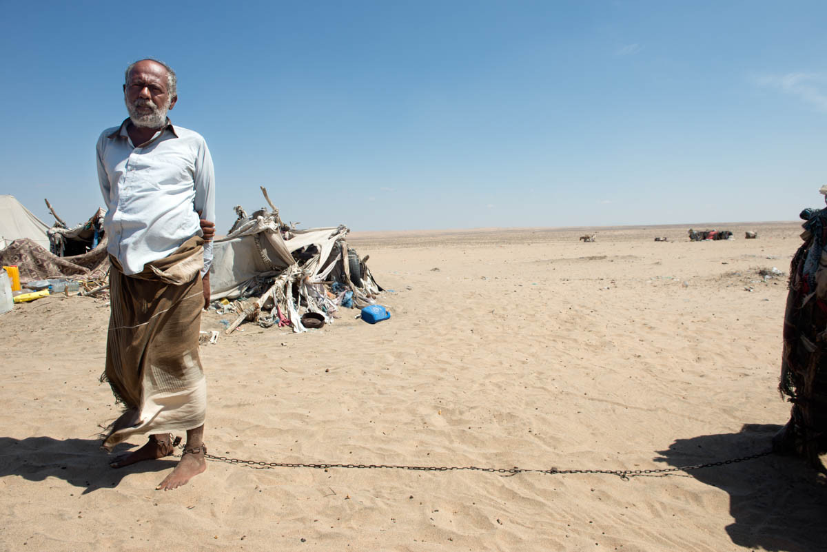 Một người đàn ông tâm thần bị xích cạnh túp lều của gia đình ông trên sa mạc Omran.