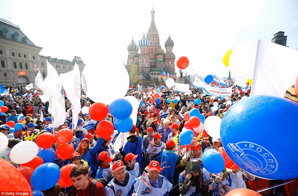 Người dân mang theo cờ, hoa và bóng bay khi tham gia diễu hành ở khu vực Quảng trường Đỏ của thủ đô Moscow.