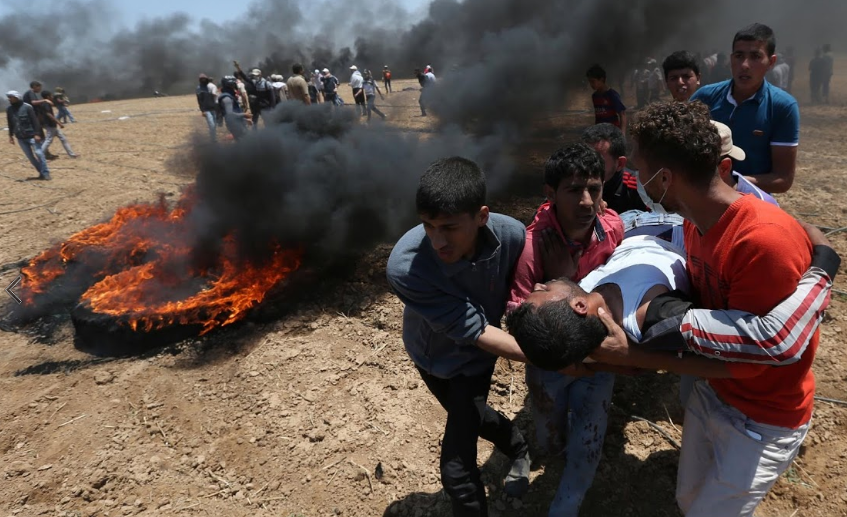 Một người biểu tình Palestine bị thương được đưa ra khỏi khu vực xung đột.