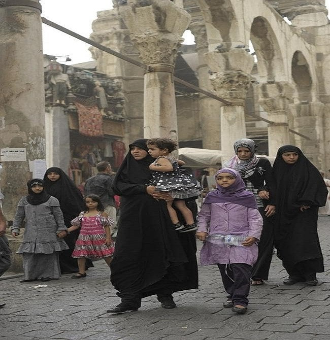 Những người phụ nữ Syria đưa con đi dạo trên một con phố ở Damascus. Ảnh: AP.