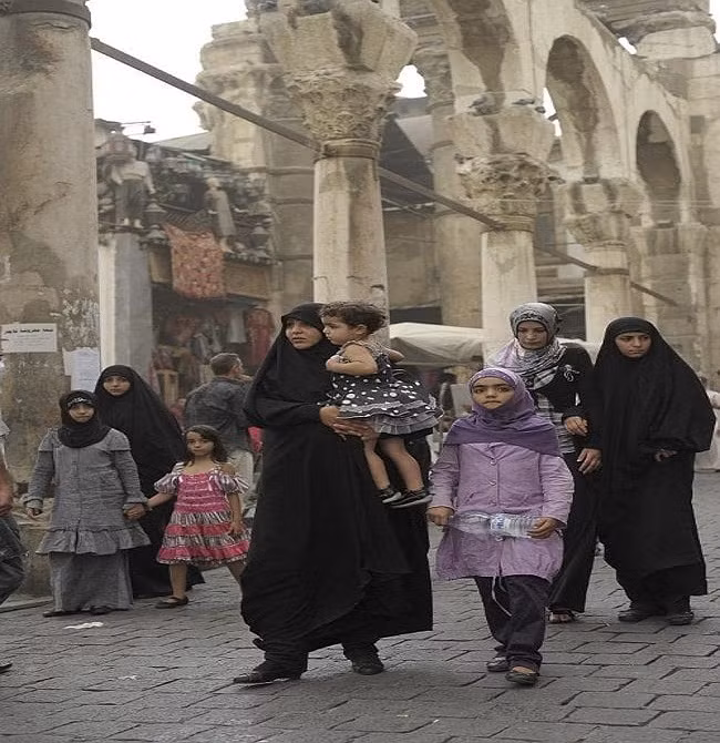 Những người phụ nữ Syria đưa con đi dạo trên một con phố ở Damascus. Ảnh: AP.