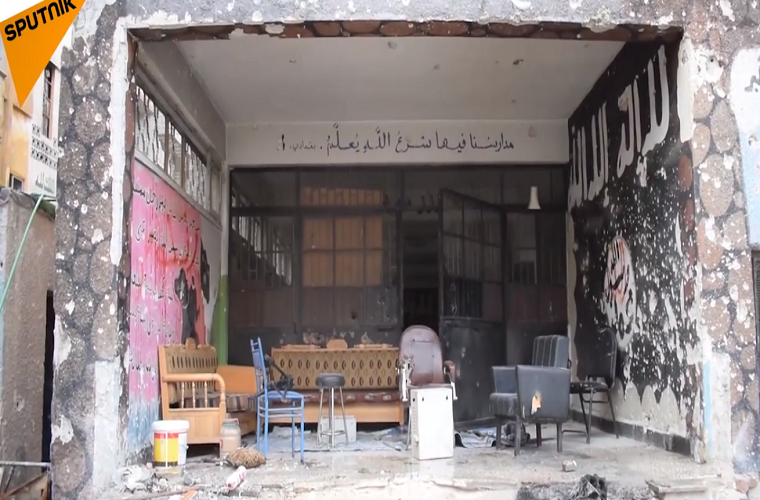 Có thể thấy, nhiều bức tường trong trường học đã bị sơn màu đen và có những khẩu hiệu của nhóm khủng bố IS. Ảnh: Sputnik.