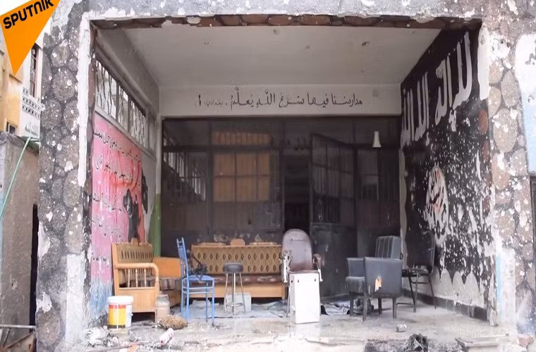 Có thể thấy, nhiều bức tường trong trường học đã bị sơn màu đen và có những khẩu hiệu của nhóm khủng bố IS. Ảnh: Sputnik.