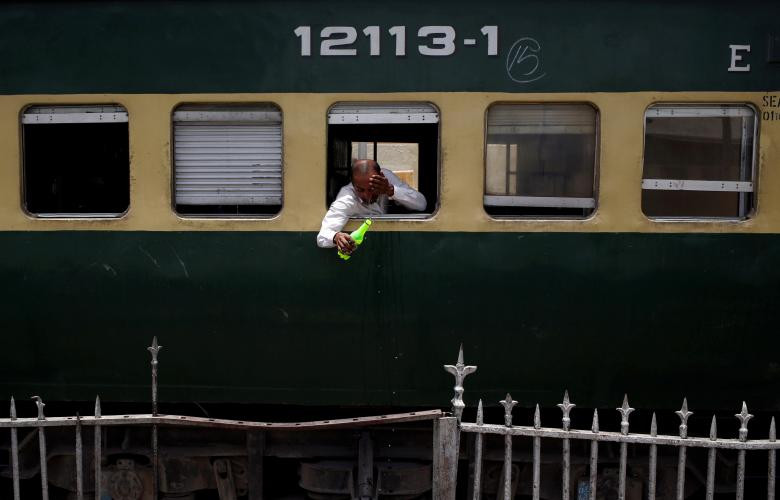 Một hành khách phải đổ nước vào mặt khi ngồi trên tàu ở Karachi.