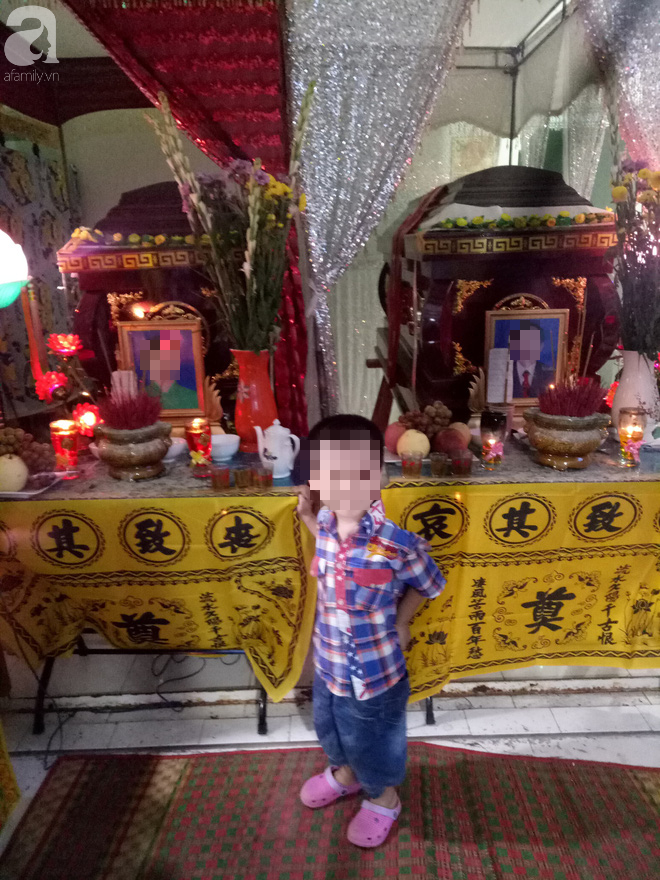 Bé Tý ngây ngô bên linh cữu của bố mẹ.