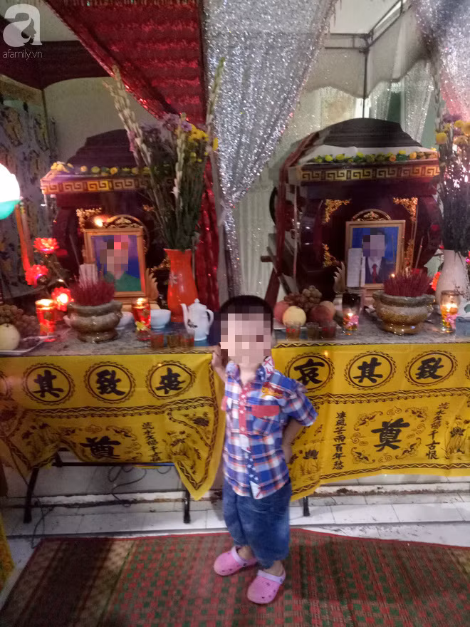 Bé Tý ngây ngô bên linh cữu của bố mẹ.