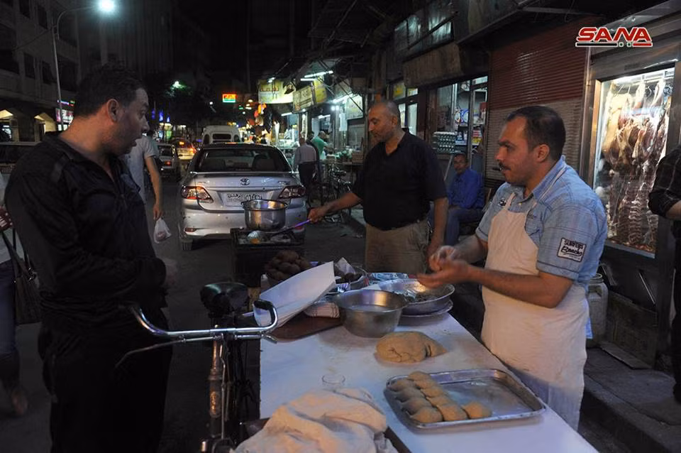 Một người dân dừng lại mua bánh được làm trực tiếp trên đường phố Damascus. Ảnh: SANA.