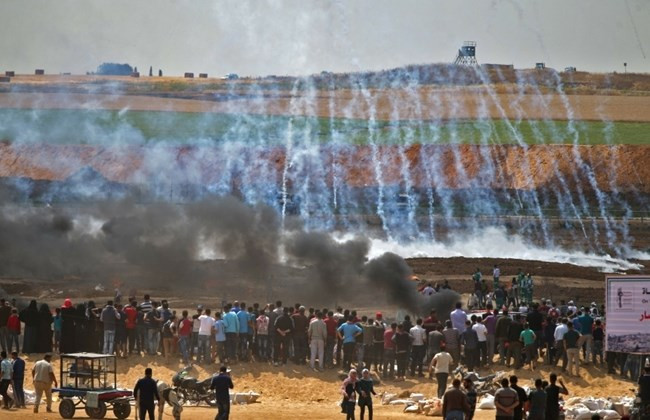 Người biểu tình Palestine đứng nhìn hơi cay mù mịt và khói đen bốc lên từ những chiếc lốp xe bốc cháy ở phía đông thành phố Gaza hôm 14/5. Ảnh: Daily Star.